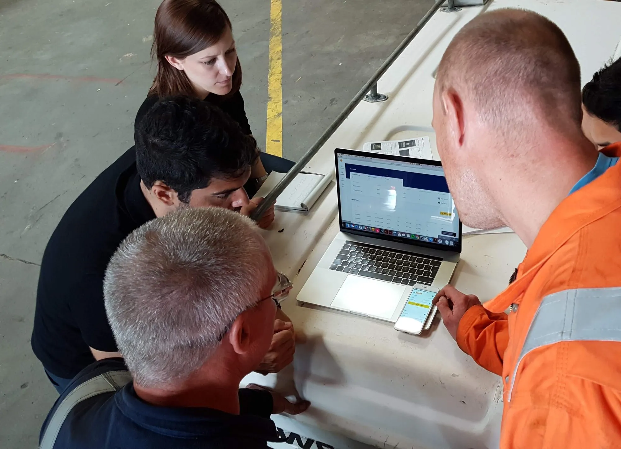 Engineers in the equipment warehouse testing the prototype on a laptop and phone